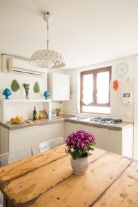 a kitchen with a wooden table with a vase of flowers on it at Manidibianco Apulian Relaxing Stay in Turi