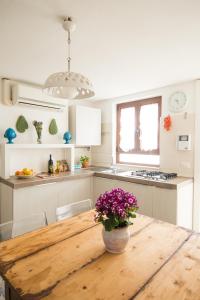 una cocina con una mesa de madera con un jarrón de flores. en Manidibianco Apulian Relaxing Stay, en Turi