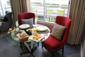 een tafel met twee rode stoelen en een tafel met eten erop bij RENT-INN Suites Hotel in Rabat
