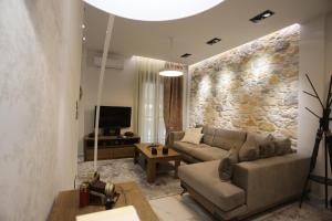 a living room with a couch and a stone wall at LA Larissa Luxury Apartments Peneus in Larisa