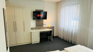 Zimmer mit einem Schreibtisch und einem TV an der Wand in der Unterkunft Creativ Park Hotel in Nürnberg