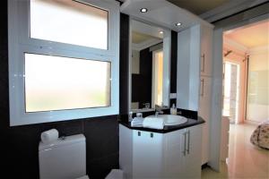 a bathroom with a sink and a mirror and a toilet at Villa Lovisi in Maspalomas