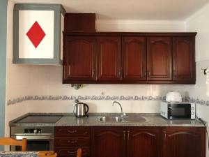 a kitchen with wooden cabinets and a sink at Camping Villa Park Zambujeira do Mar in Zambujeira do Mar