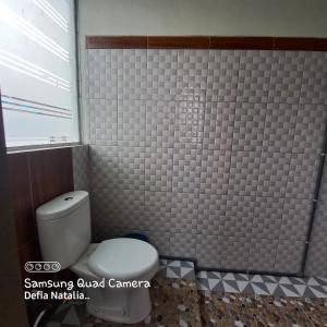 a bathroom with a toilet and a tiled wall at Bromo Deddy Homestay in Bromo