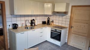 a small kitchen with white cabinets and a sink at Familie Seibert in Bergen