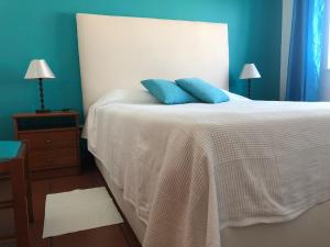 a bedroom with a bed with two blue pillows on it at Camping Villa Park Zambujeira do Mar in Zambujeira do Mar