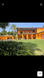 a large orange building with a palm tree in front of it at La Dulcinea in Sotogrande