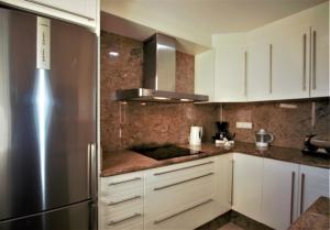 a kitchen with white cabinets and a stainless steel refrigerator at Villa Lovisi in Maspalomas