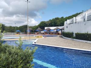 a swimming pool with tables and umbrellas at a resort at Condomínio encantador próximo a praia , 3 quartos. in João Pessoa
