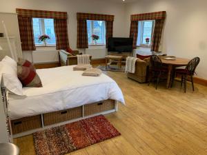 a bedroom with a bed and a living room with a table at The Cottage at Well House in Shepton Mallet