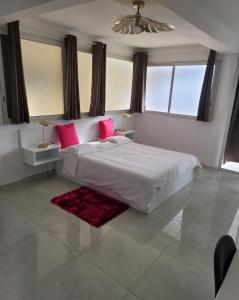 a bedroom with a large white bed with pink pillows at Hello Guyane (2), Suite Luxury, 5 étoiles in Cayenne