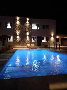 una gran piscina azul por la noche con una casa en el fondo en Divina Montaña en Mendoza