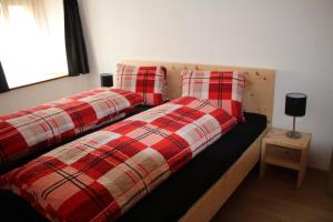 two beds with plaid pillows in a bedroom at Chasa Allegra Müstair in Müstair