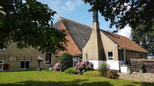 a church with a steeple and flowers in the yard at Âlde Bakhûs in Sondel