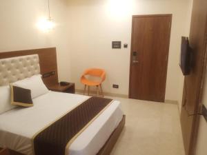 a bedroom with a bed and a chair and a door at Paras Mahal in Vellore