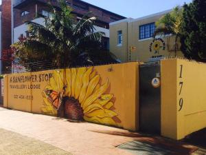 una pared con una pintura de una piña y una mariposa en A Sunflower Stop Backpackers, en Ciudad del Cabo