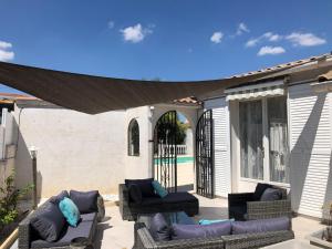 un patio avec des canapés et des chaises sous un auvent dans l'établissement Villa du sud ouest, à Béziers