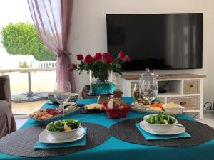une table avec des assiettes de nourriture et une télévision dans l'établissement Villa du sud ouest, à Béziers