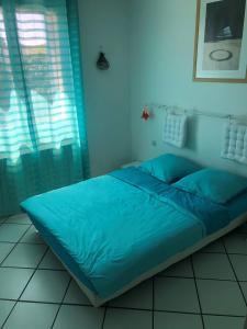 - un lit avec des draps bleus dans une chambre avec une fenêtre dans l'établissement Villa du sud ouest, à Béziers