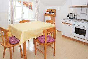 eine Küche mit einem Tisch und 2 Stühlen sowie eine Küche mit einem Herd in der Unterkunft Weinhof Gregor Raab in Unterretzbach