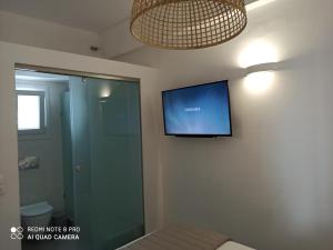 Habitación con TV de pantalla plana en la pared en Kleri's apartments 2 en Tinos Town