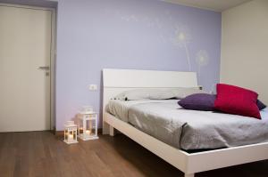a bedroom with a white bed with purple pillows at Il nido di Marty in Issogne