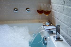 two glasses of wine sitting on a bath tub with water at Il nido di Marty in Issogne