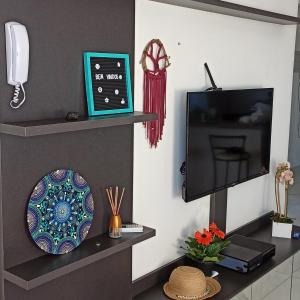 een kamer met een tv en een bord en een klok bij Apartamento Ingleses in Florianópolis