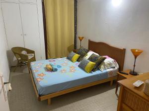 een slaapkamer met een bed met blauwe lakens en kussens bij Maison Petit Paradis in Basse-Terre