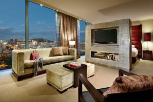 a living room with a tv and a large window at Hyatt Regency Barcelona Tower in Hospitalet de Llobregat