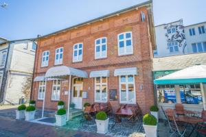 a brick building with tables and chairs in front of it at Schneewittchen in Westerland