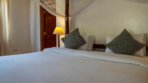 a bedroom with a white bed with pillows on it at Black Wattle House in Nakuru