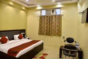 a bedroom with a bed and a desk and a window at Hotel Nexus in Lucknow