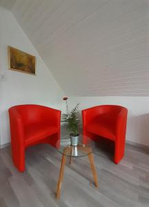 two red chairs and a table in a room at FeWo Karola in Ellenz-Poltersdorf