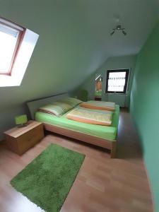 a green bedroom with a bed and a window at FeWo Karola in Ellenz-Poltersdorf