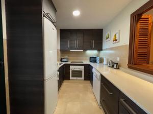 cocina con armarios negros y nevera blanca en HL 005 2 Bedroom Apartment,HDA golf resort, Murcia, en Murcia