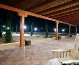 a patio with two white chairs and a wooden roof at Granja escuela con bungalows Familias y grupos Parking privado gratuito in San Martín de la Vega +12 photos