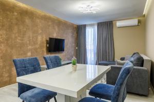 a living room with a white table and blue chairs at Баня Аква Ризорт in Banya