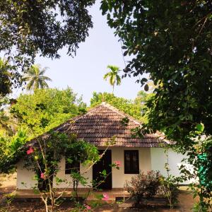 a small white house with a thatched roof at Munroe Inn Homestay in Kollam