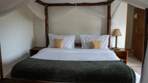 um quarto com uma cama grande com lençóis brancos e almofadas em Yellowwood House em Nakuru