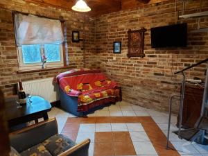 uma sala de estar com um sofá e uma televisão e uma parede de tijolos em Na Pograniczu domek w górach em Lasowka