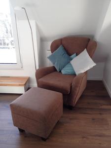ein Wohnzimmer mit einem Stuhl und einer Ottomane in der Unterkunft Feriendomizil Ösetalblick in Bad Driburg