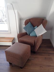 a living room with a chair and a ottoman at Feriendomizil Ösetalblick in Bad Driburg