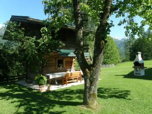 une cabane en rondins avec un banc et un arbre dans l'établissement Krennlehen, à Schönau am Königssee