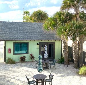 a patio with tables and chairs and palm trees at Organic Beach Retreat in Daytona Beach