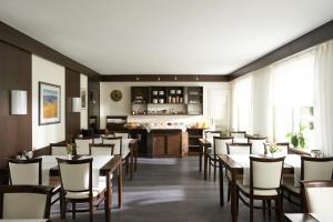 a dining room with tables and chairs and a kitchen at Hotel Klughardt in Nuremberg