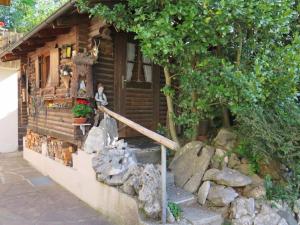 uma pequena cabana de madeira com uma árvore e algumas pedras em Ferienwohnung Aiblinger em Frasdorf