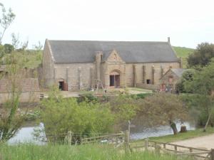 Una vieja iglesia con un río delante. en East Farm House B&B, en Abbotsbury