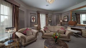 a living room with chairs and a table and a mirror at Midlands Park Hotel in Portlaoise