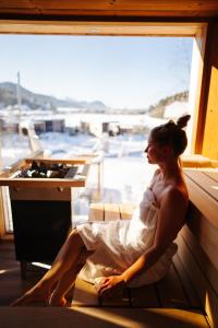 Una mujer con un vestido blanco sentada en una ventana en Lakeside Petzen Glamping, en Unterlibitsch